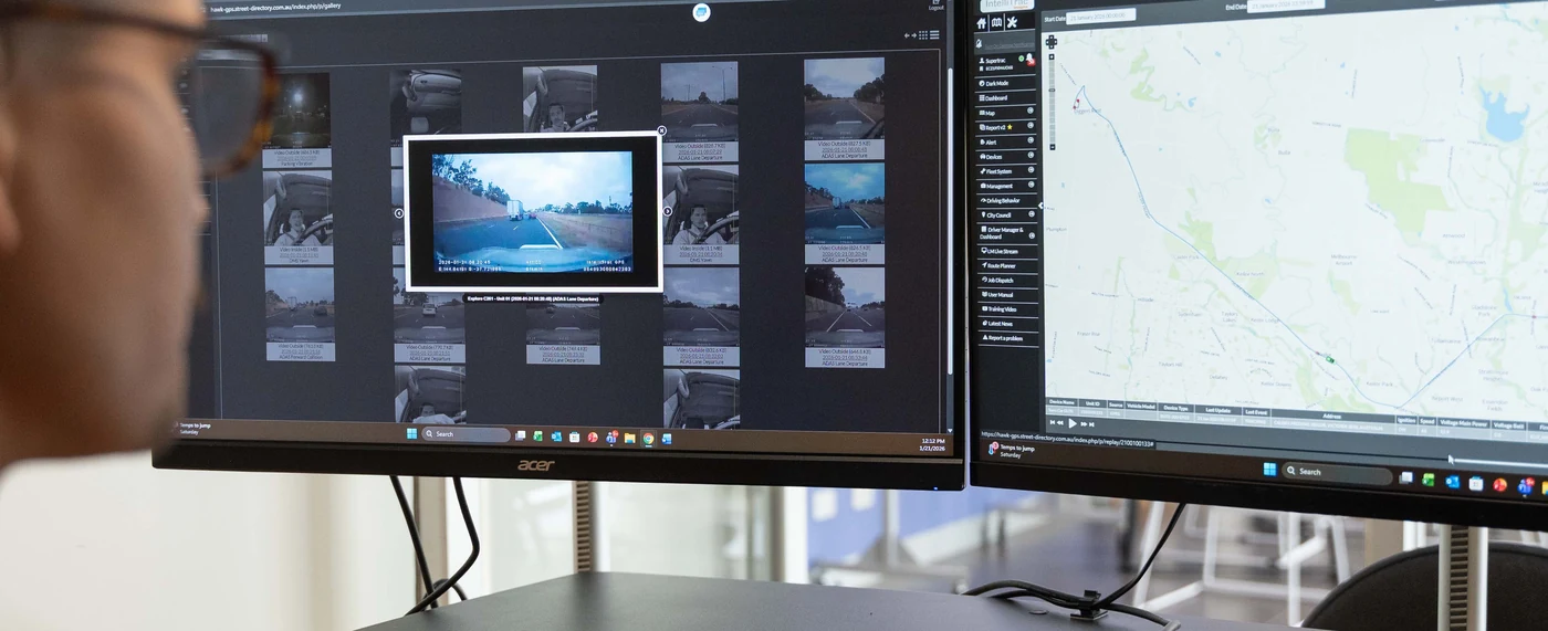 IntelliTrac operator reviewing live video and fleet software on desktop monitors.
